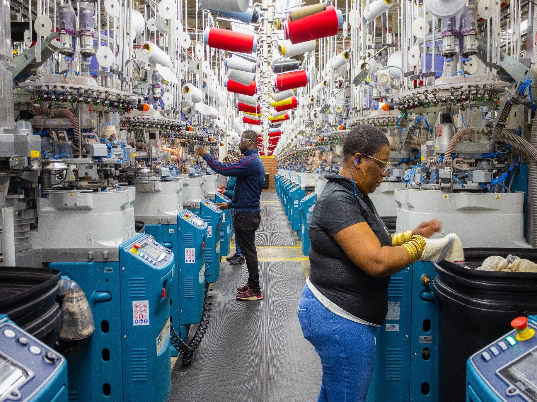 Two rows of sock knitting machines, and a few employees that operate them